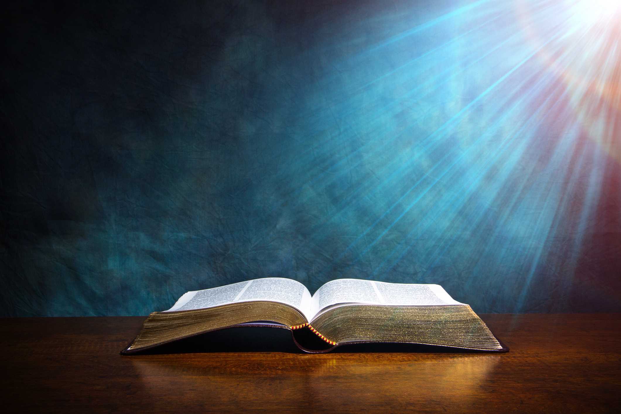 An open Bible illuminated against a deep blue background